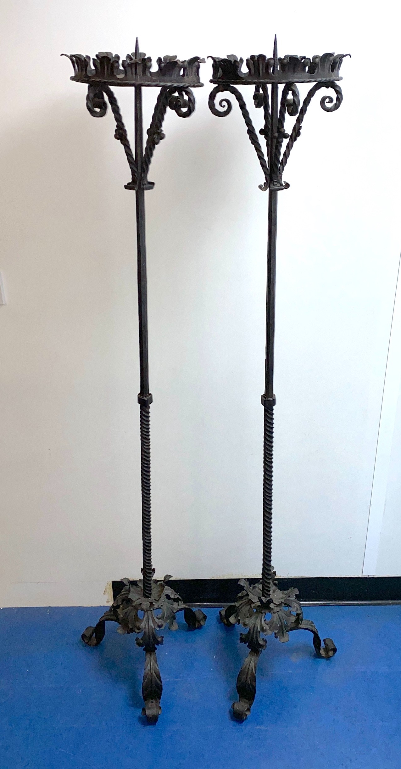 A pair of wrought iron Prickett lamp standard candlesticks, in the 18th century manner, height 157cm. width of base 38cm.